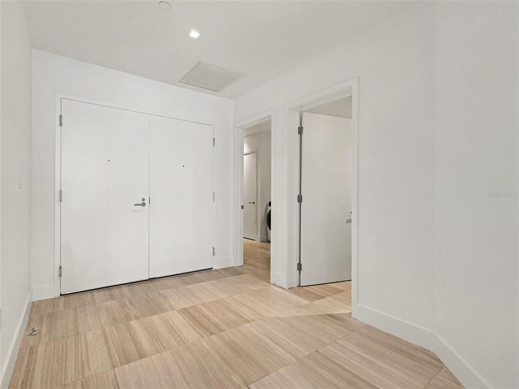 A hallway with light wood-look tile flooring, white walls, and several closed interior doors — 3101 W BAYSHORE STREET UNIT 502, TAMPA, FL