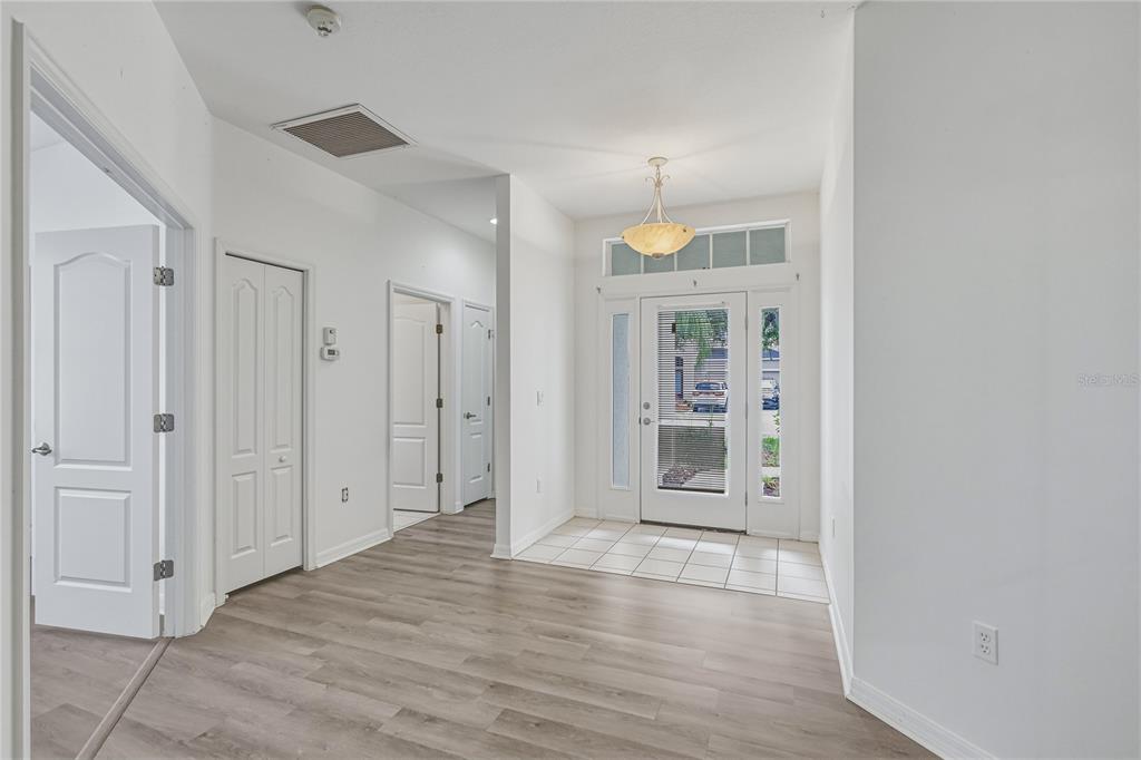 An entryway with light wood-look flooring, white walls, a tiled landing, and a front door — 4603 TROUT RIVER CROSSING, ELLENTON, FL