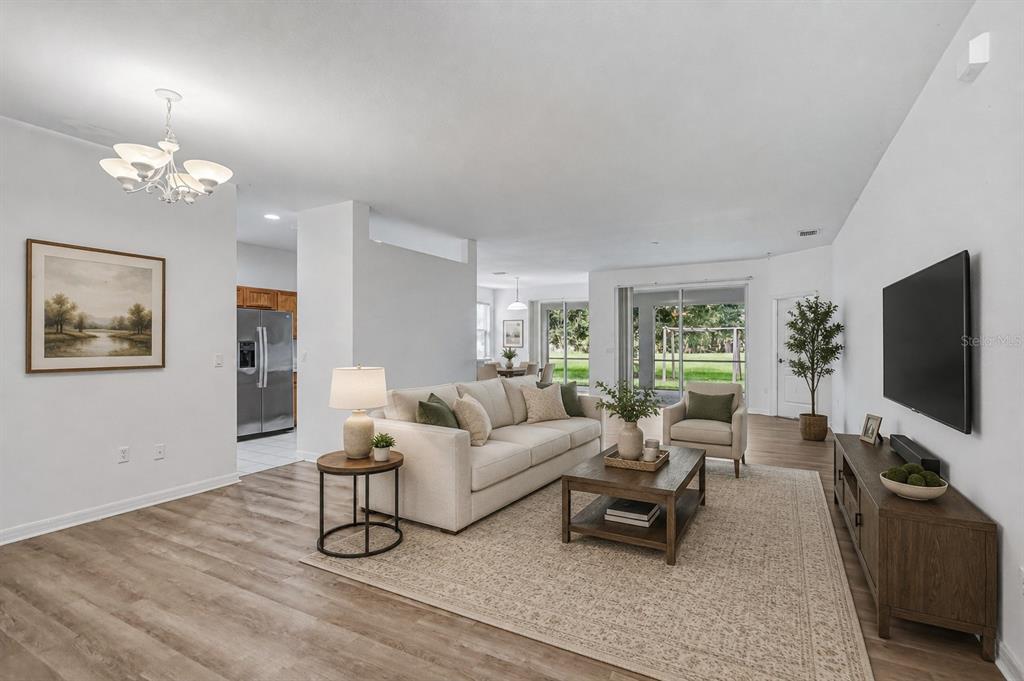A living room features a beige sofa, a wooden coffee table, and a wall-mounted television — 4603 TROUT RIVER CROSSING, ELLENTON, FL