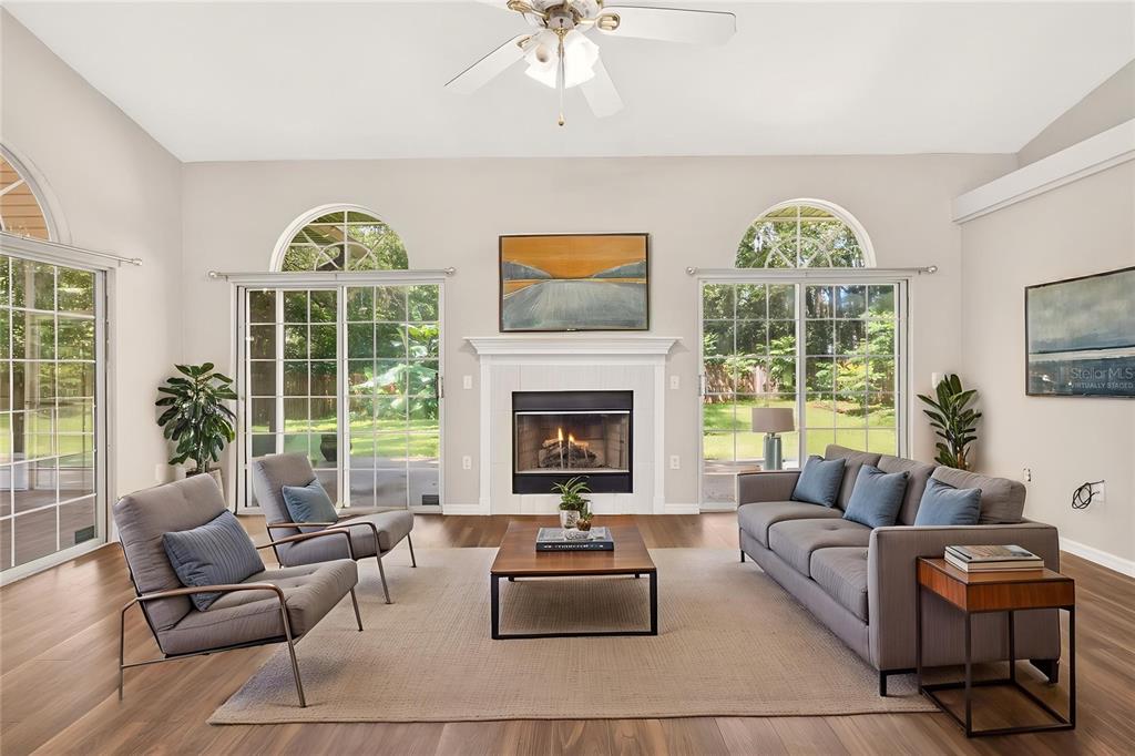 A living room features a fireplace, two sliding glass doors, and a gray sofa set — 1124 NW 98TH TERRACE, GAINESVILLE, FL
