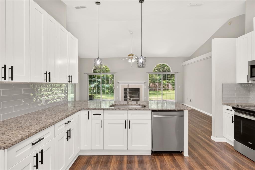 A kitchen with white cabinets, granite countertops, a gray subway tile backsplash, and stainless appliances — 1124 NW 98TH TERRACE, GAINESVILLE, FL