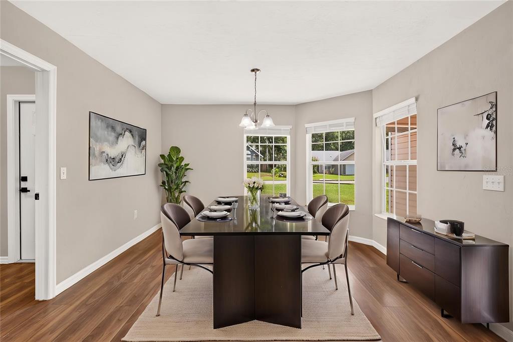 A dining room with a dark wood table, chairs, a sideboard, and large windows — 1124 NW 98TH TERRACE, GAINESVILLE, FL