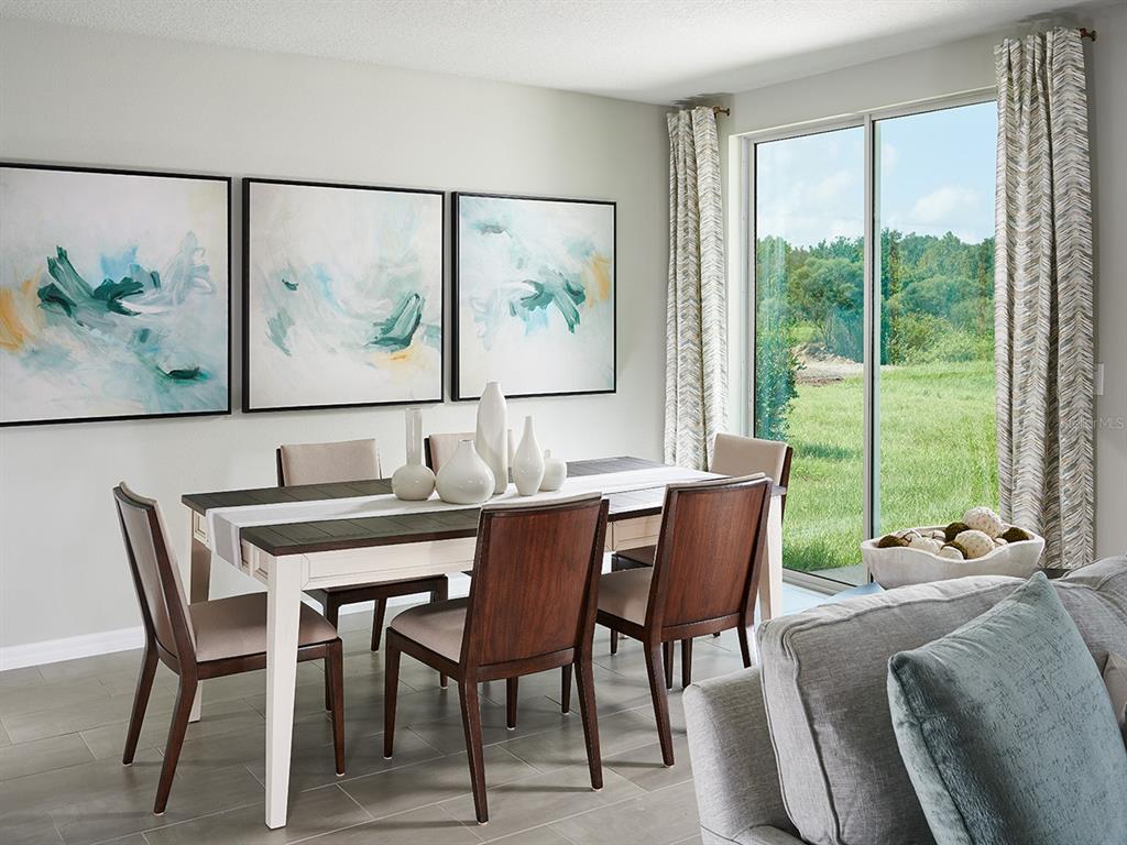 A dining room features a wooden table, six chairs, abstract wall art, and sliding glass doors — 1008 MONARCH PASS, LAKE HAMILTON, FL