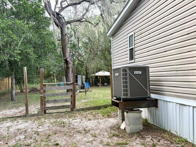 An outdoor air conditioning unit sits on a metal stand supported by concrete blocks — 9825 LEGUNA STREET, NEW PORT RICHEY, FL