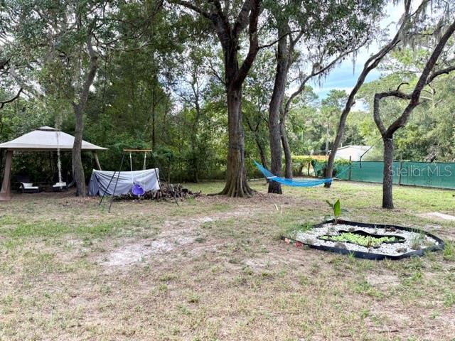 A backyard features a gazebo, a swing set, a hammock, and a small garden bed — 9825 LEGUNA STREET, NEW PORT RICHEY, FL