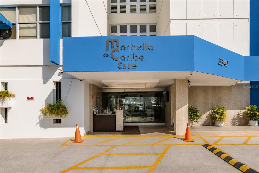 The exterior entrance of a building features a blue awning with the name Marbella del Caribe — MARBELLA DEL CARIBE ESTE # 301, CAROLINA, PR