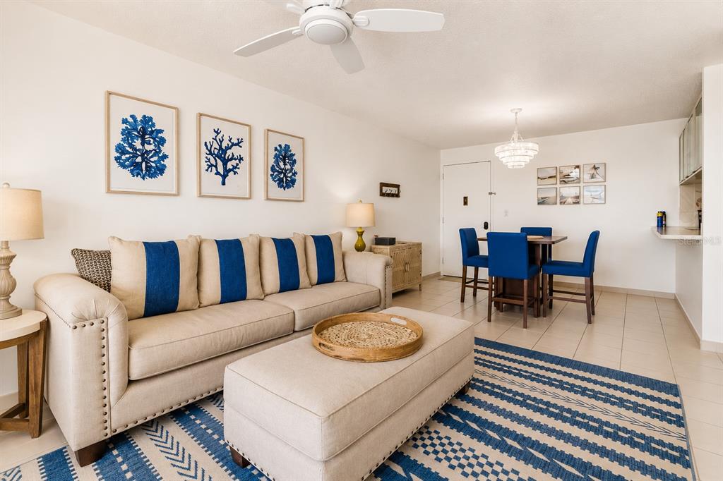 A living room with a beige sofa, matching ottoman, and a dining area with blue chairs — MARBELLA DEL CARIBE ESTE # 301, CAROLINA, PR