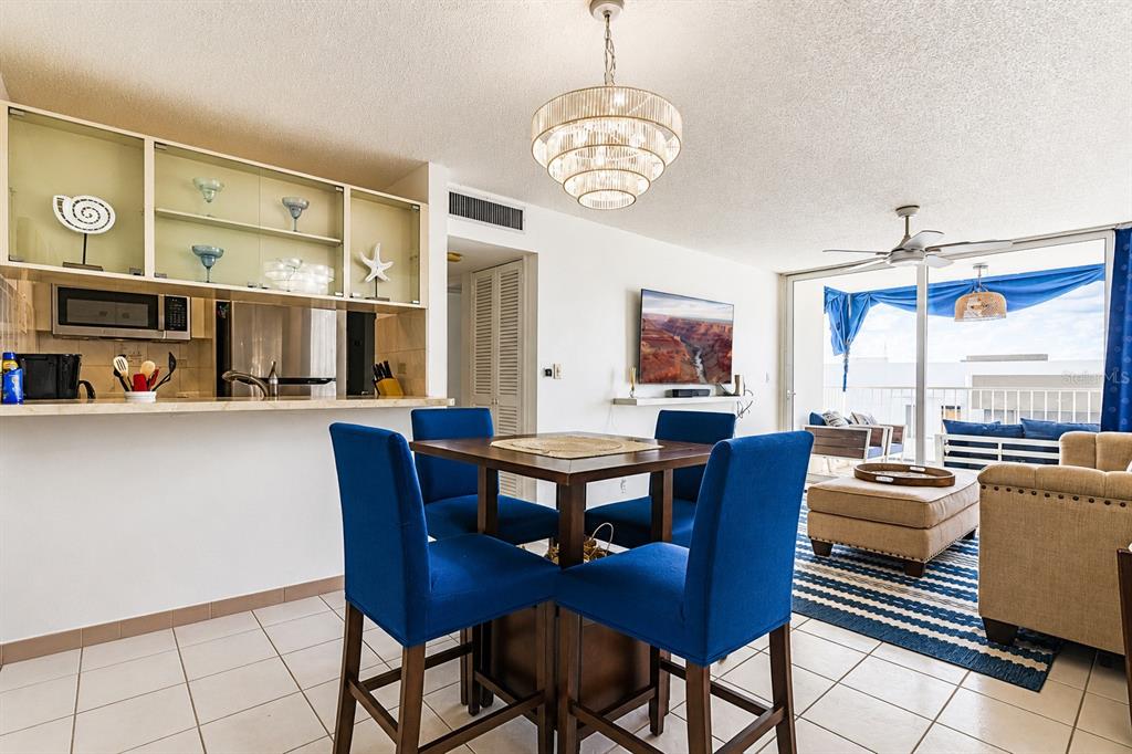 A dining area with blue chairs sits before a kitchen, living space, and balcony — MARBELLA DEL CARIBE ESTE # 301, CAROLINA, PR