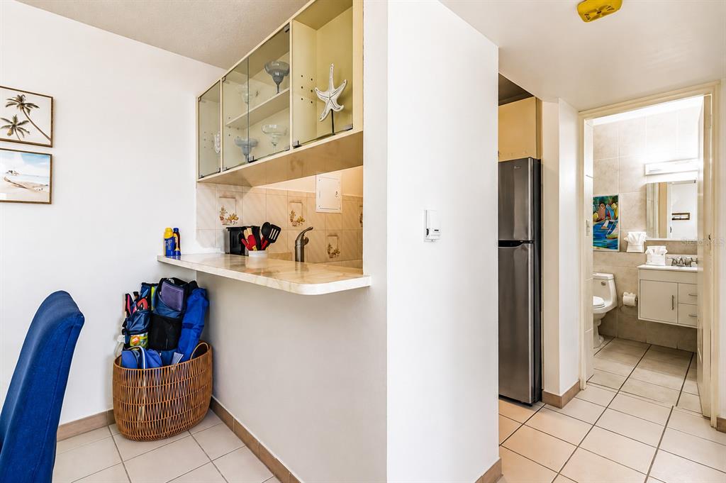 A kitchen pass-through counter with upper cabinets overlooks a dining area next to a bathroom — MARBELLA DEL CARIBE ESTE # 301, CAROLINA, PR