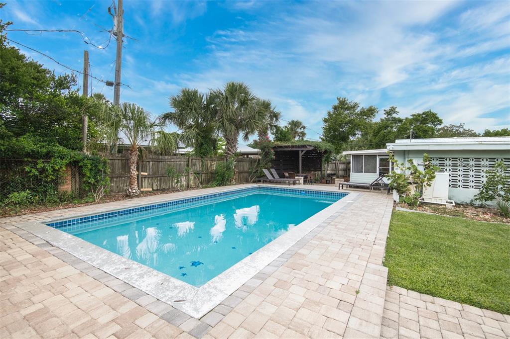 A rectangular swimming pool sits in a backyard with a paver patio and wooden fence — 159 SOUTHWIND (POOL HOME) CIRCLE, ST AUGUSTINE, FL