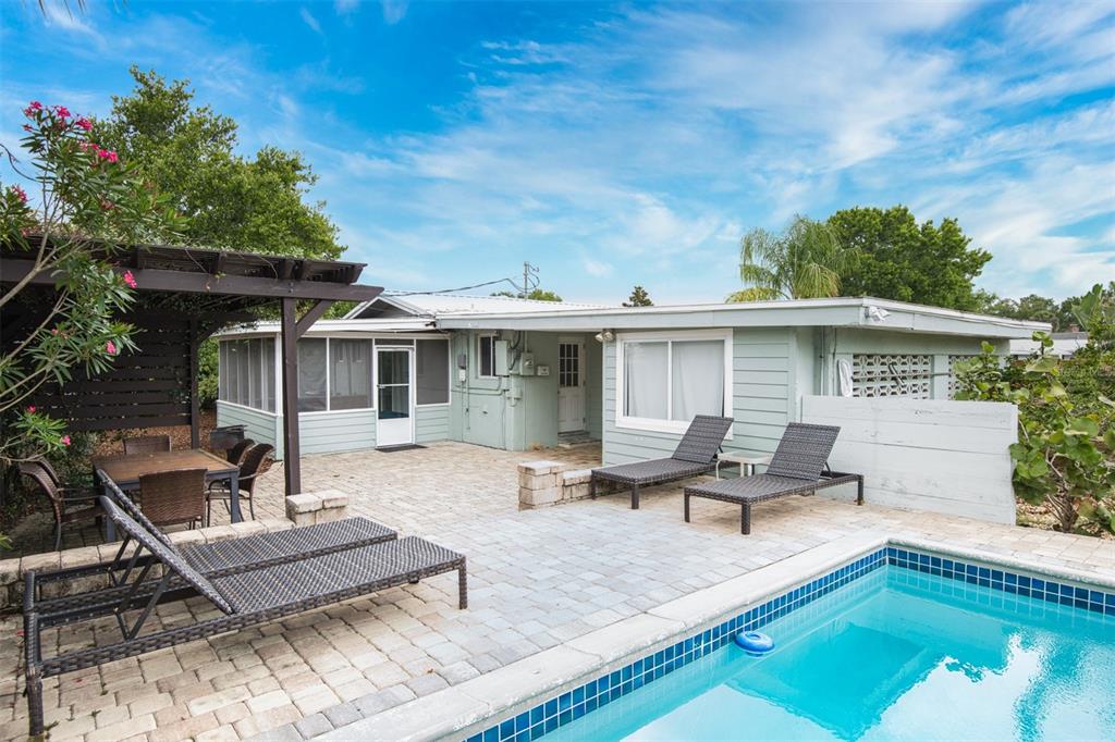 A backyard patio features a swimming pool, lounge chairs, a dining area, and a pergola — 159 SOUTHWIND (POOL HOME) CIRCLE, ST AUGUSTINE, FL