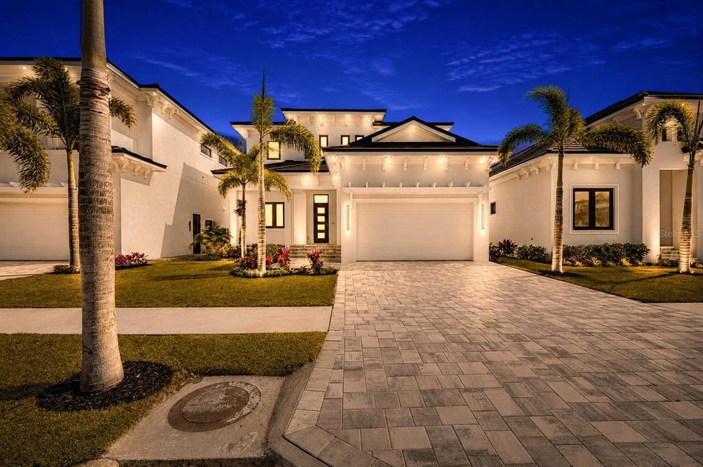 A modern white house with a paved driveway and palm trees at dusk — 6538 SIMONE SHORES CIRCLE, APOLLO BEACH, FL