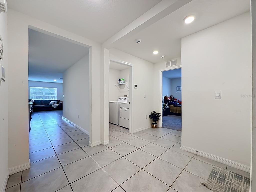 A tiled hallway leads to a laundry closet, a bedroom, and a living area — 16661 WINDMILL FORGE PASS, WIMAUMA, FL