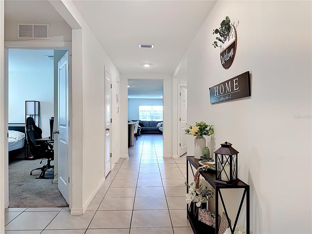 A tiled hallway leads to a living area, featuring a console table and wall decor — 16661 WINDMILL FORGE PASS, WIMAUMA, FL
