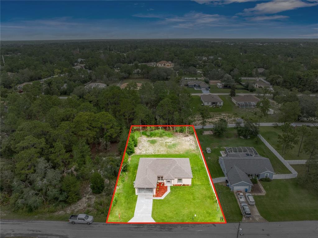 An aerial view shows a single-story house with a concrete driveway and a large backyard — 11277 FOOL DUCK AVENUE, WEEKI WACHEE, FL