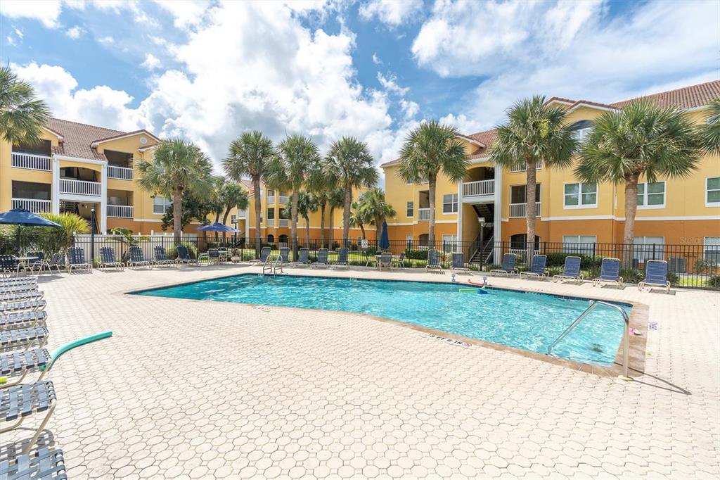 An outdoor swimming pool surrounded by a paved deck, lounge chairs, and apartment buildings — 10764 70TH AVENUE UNIT 3307, SEMINOLE, FL
