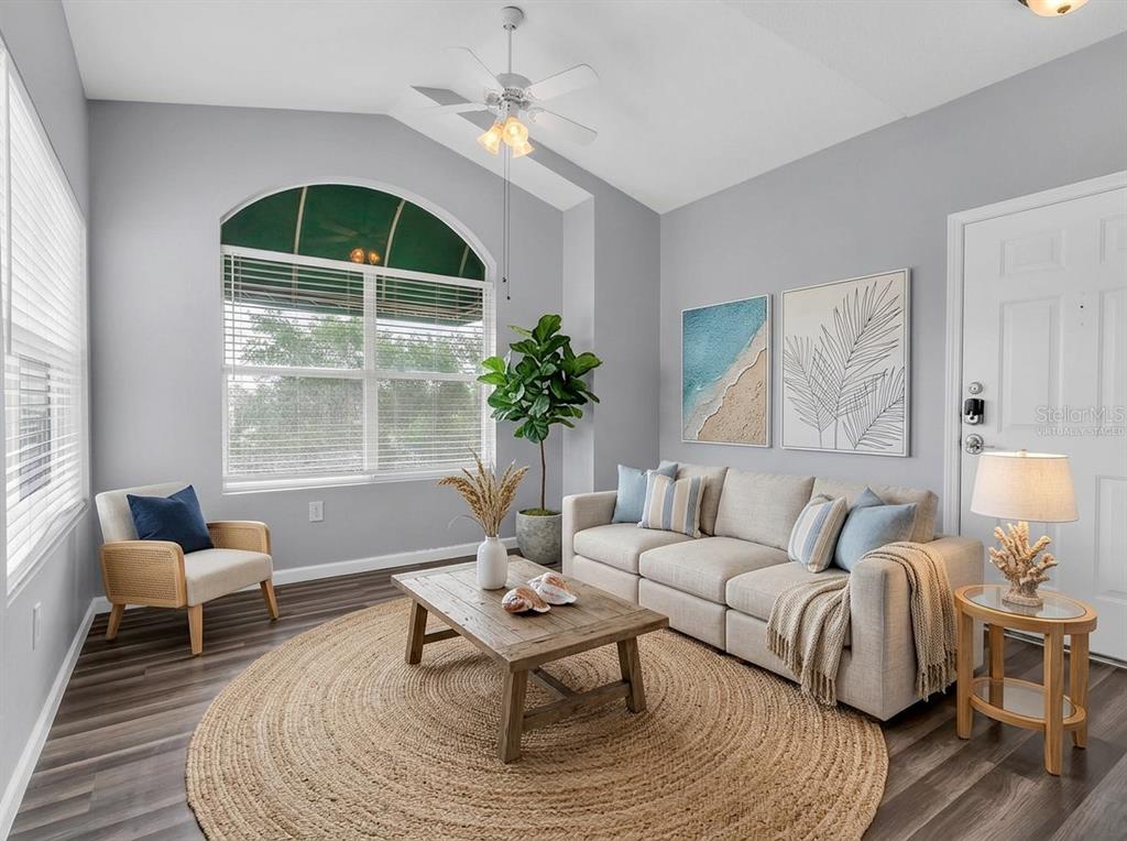 A living room with gray walls, wood-look flooring, a vaulted ceiling, and a large window — 10764 70TH AVENUE UNIT 3307, SEMINOLE, FL