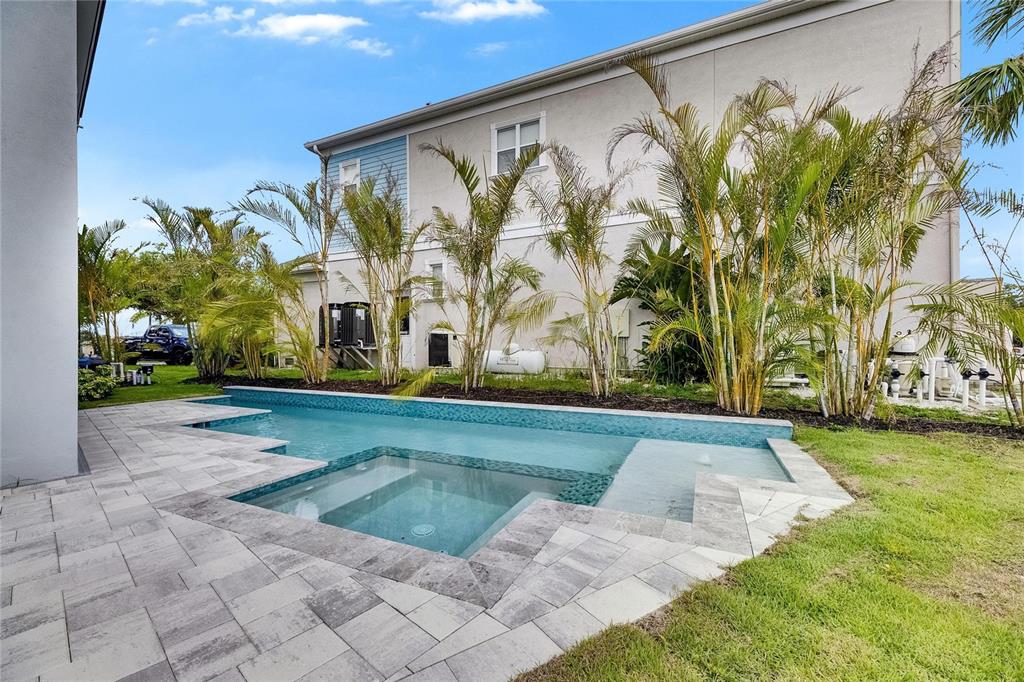 A backyard swimming pool with an integrated spa and stone paver patio beside a house — 6526 SIMONE SHORES CIRCLE, APOLLO BEACH, FL