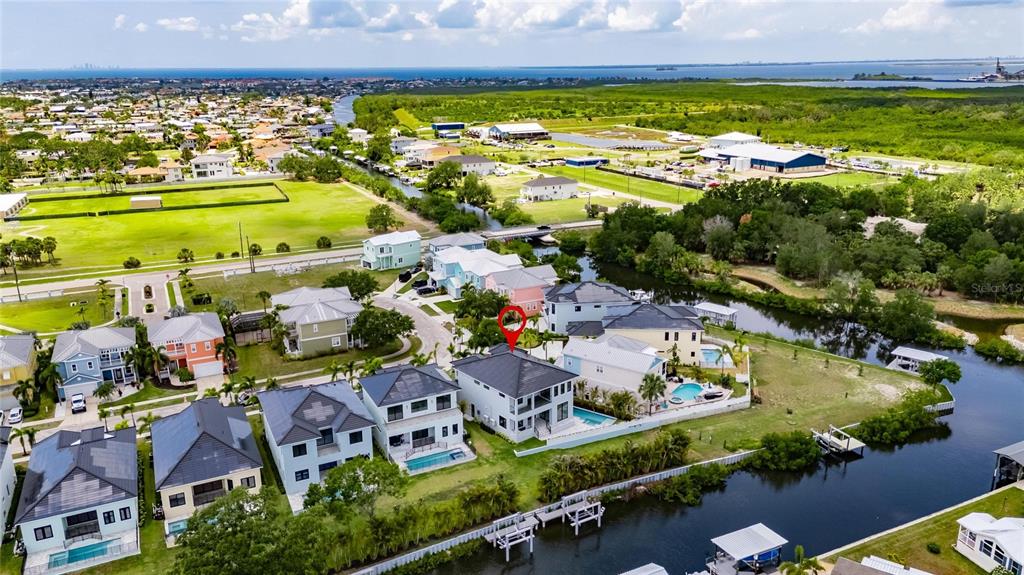 An aerial view shows a multi-story house with a pool situated along a canal — 6526 SIMONE SHORES CIRCLE, APOLLO BEACH, FL