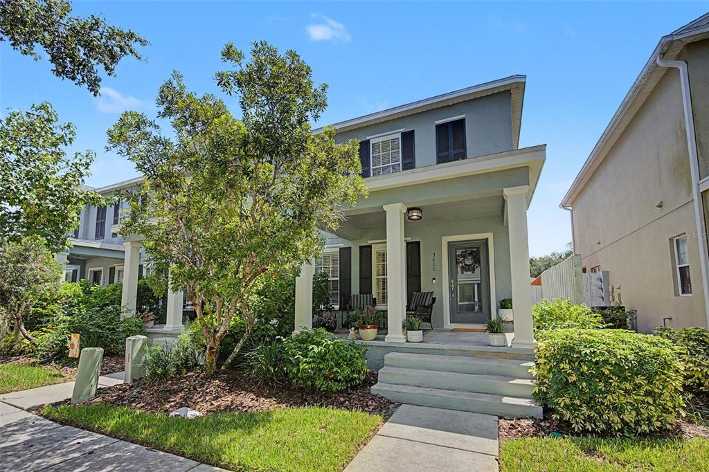 A two-story house with a front porch, columns, and a landscaped yard under a blue sky — 3800 HERLONG STREET, NEW PORT RICHEY, FL