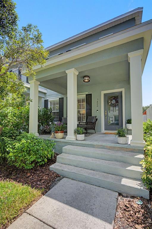 A front porch with concrete steps, white columns, and a gray door on a house — 3800 HERLONG STREET, NEW PORT RICHEY, FL