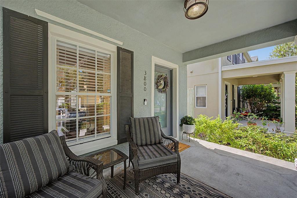 A covered front porch features two wicker chairs, a small table, and a patterned rug — 3800 HERLONG STREET, NEW PORT RICHEY, FL