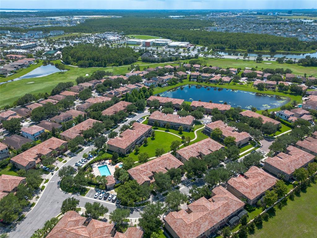 An aerial view shows a residential community with townhomes, a swimming pool, and a lake — 8349 KELSALL DRIVE, ORLANDO, FL