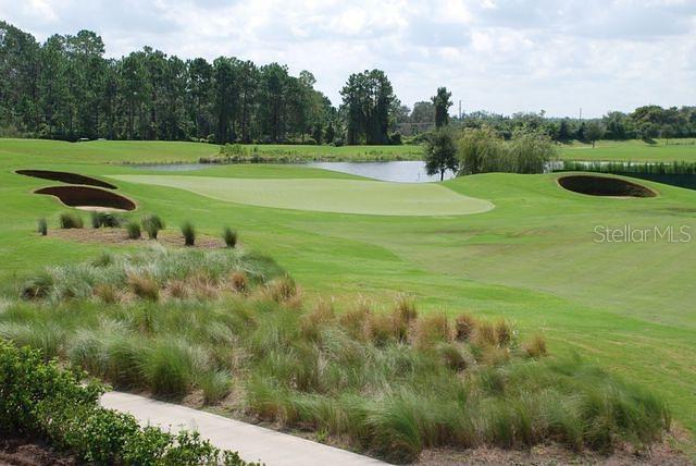 A view of a golf course green surrounded by sand bunkers, water, and trees — 8349 KELSALL DRIVE, ORLANDO, FL