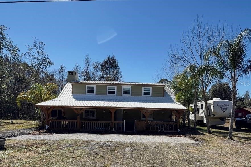 A two-story house with a metal roof and a large covered front porch — 445 S STATE ROAD 415, OSTEEN, FL
