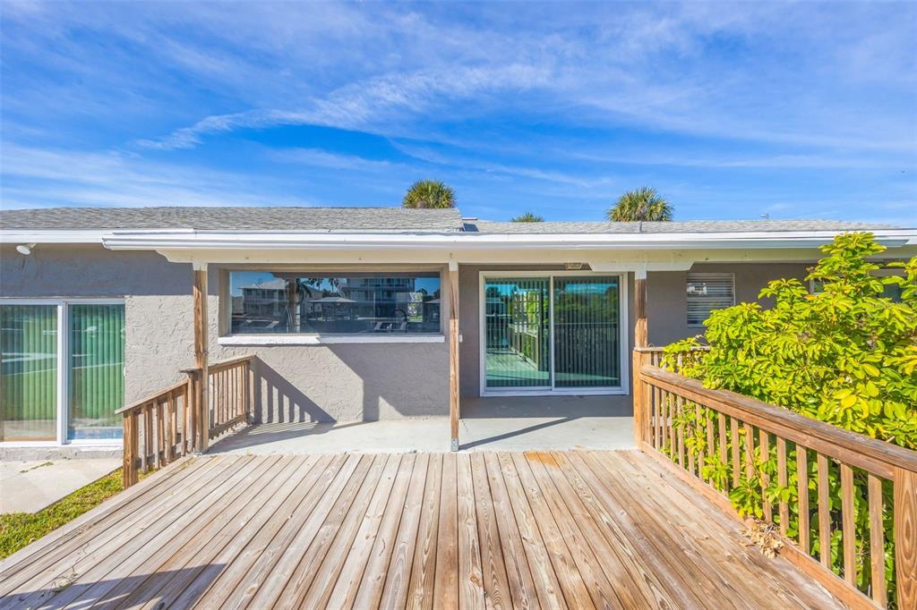 A wooden deck extends from the back of a house with sliding glass doors — 4512 HAITI DRIVE, HERNANDO BEACH, FL