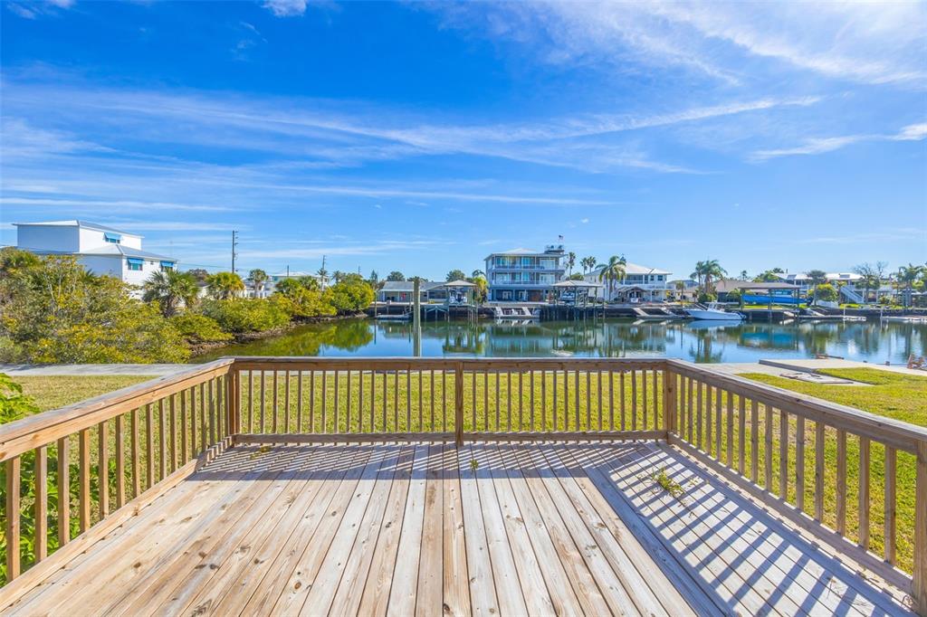 A wooden deck overlooks a calm canal with houses and boat docks on the opposite bank — 4512 HAITI DRIVE, HERNANDO BEACH, FL