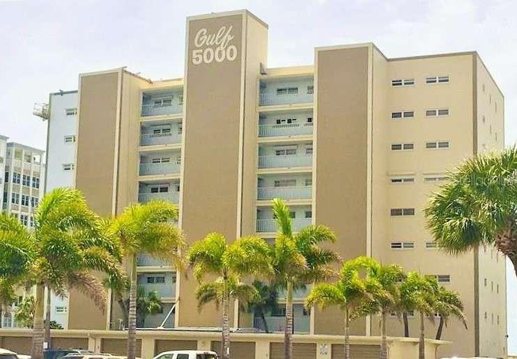 A multi-story tan apartment building features a central tower labeled Gulf 5000 and palm trees — 5000 GULF BOULEVARD UNIT 303, ST PETE BEACH, FL
