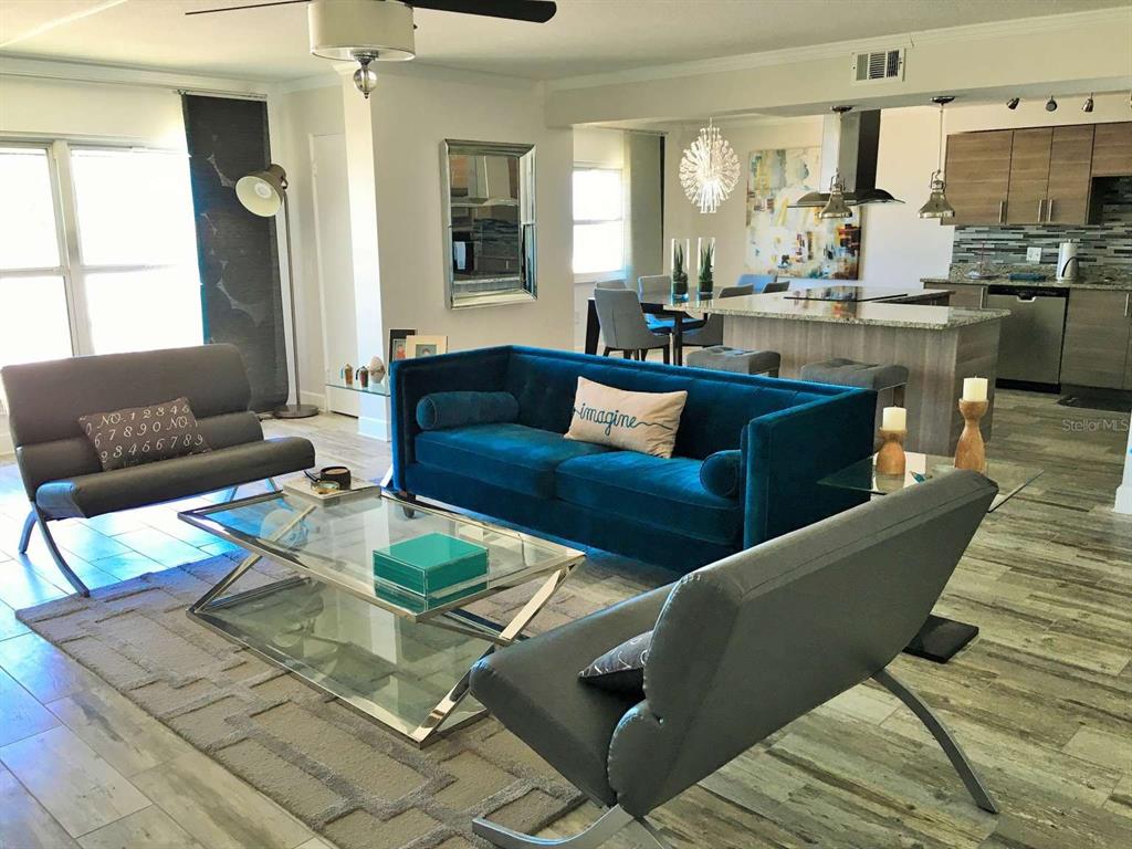 A living room features a blue velvet sofa, two gray chairs, and a glass coffee table — 5000 GULF BOULEVARD UNIT 303, ST PETE BEACH, FL
