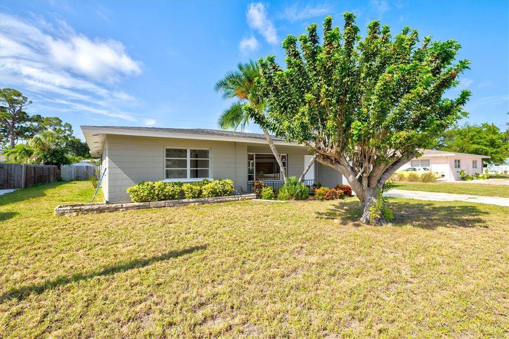 A single-story house with a light-colored exterior, a large tree, and a grassy yard — 106 AURORA STREET E, VENICE, FL