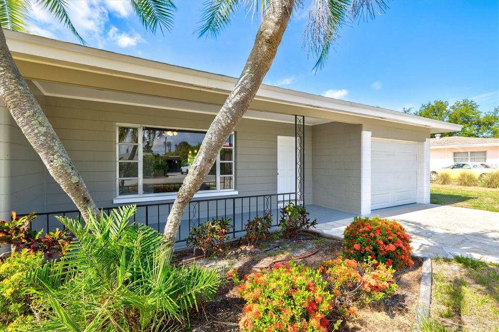 A single-story house with gray siding, a front porch, and a white garage door — 106 AURORA STREET E, VENICE, FL