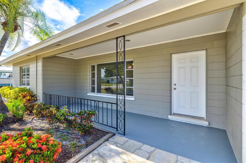 A gray house exterior features a covered porch, a white front door, and metal railings — 106 AURORA STREET E, VENICE, FL