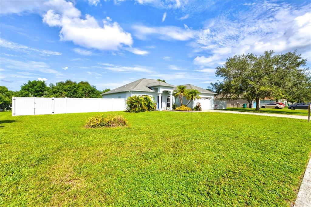 A single-story house with a white fence and a large lawn under a blue sky — 1505 22ND AVENUE W, PALMETTO, FL