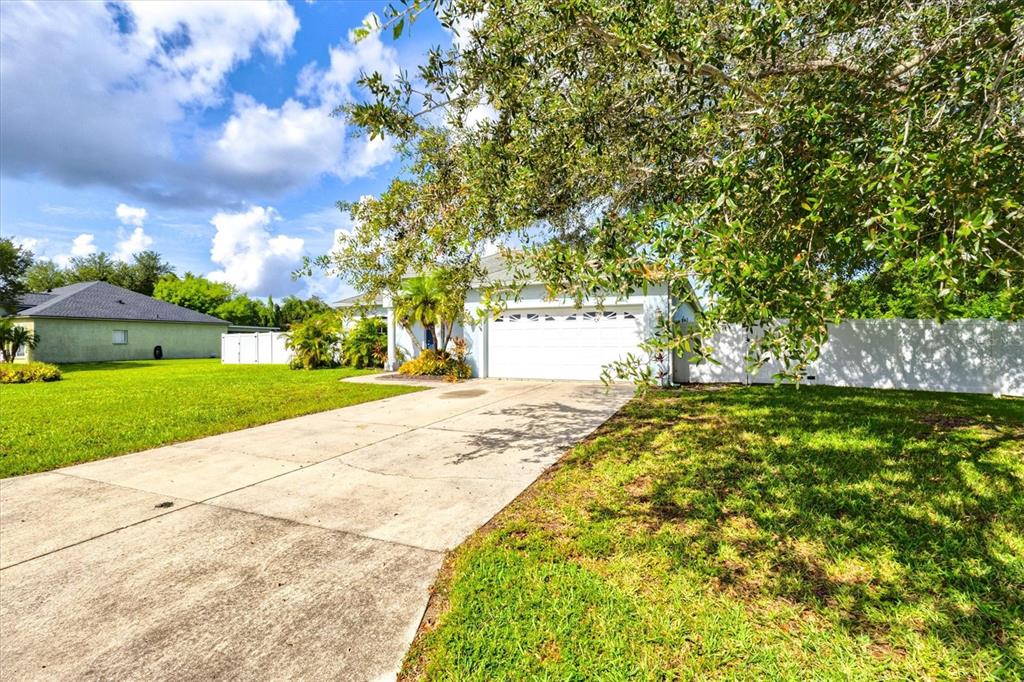 A concrete driveway leads to the garage of a single-story house with a white fence — 1505 22ND AVENUE W, PALMETTO, FL