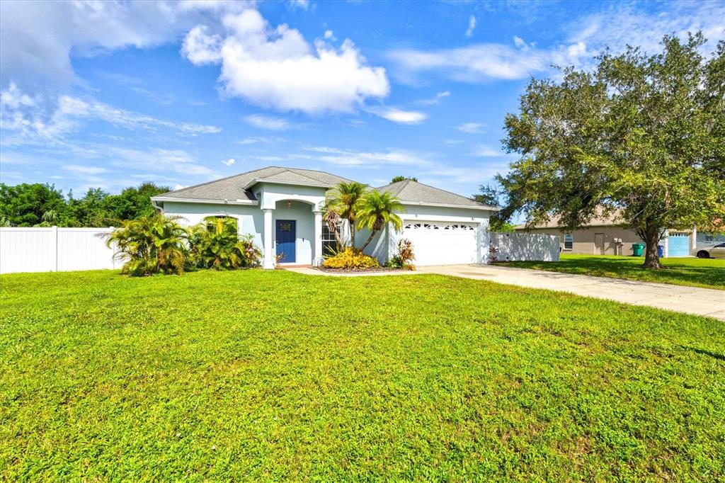 A single-story house with a blue front door, two-car garage, and a large front lawn — 1505 22ND AVENUE W, PALMETTO, FL