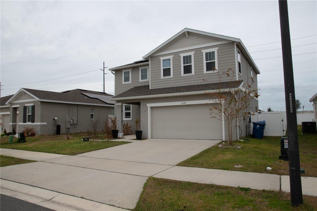 A two-story suburban house with gray siding and a two-car garage — 1054 HEIRLOOM DRIVE, HAINES CITY, FL