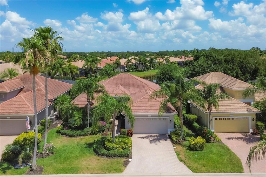 An aerial view of a suburban neighborhood featuring three single-story houses with tiled roofs — 13853 SIENA LOOP, LAKEWOOD RANCH, FL