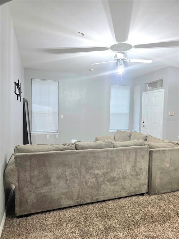 A living room features a large sectional sofa, a wall-mounted television bracket, and carpeted flooring — 1101 VINTAGE VILLAGE LANE UNIT 110, OCOEE, FL