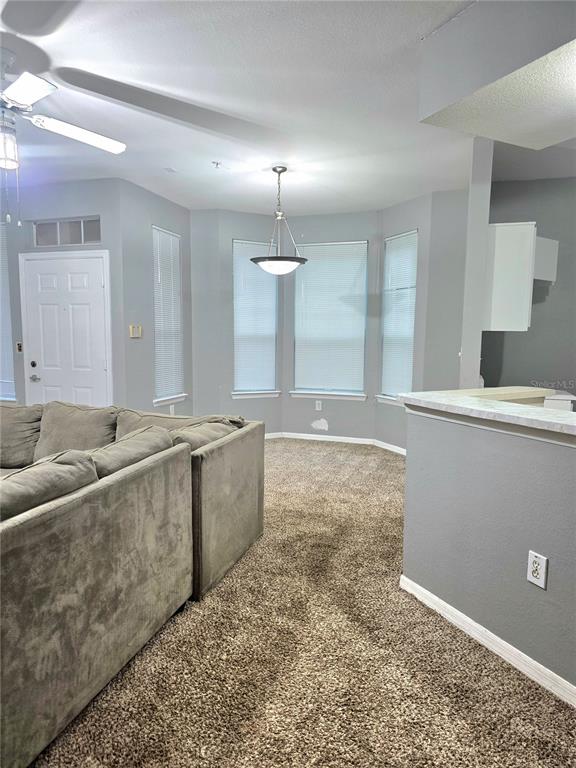 A living room features a large sectional sofa, carpeted flooring, and a ceiling fan — 1101 VINTAGE VILLAGE LANE UNIT 110, OCOEE, FL