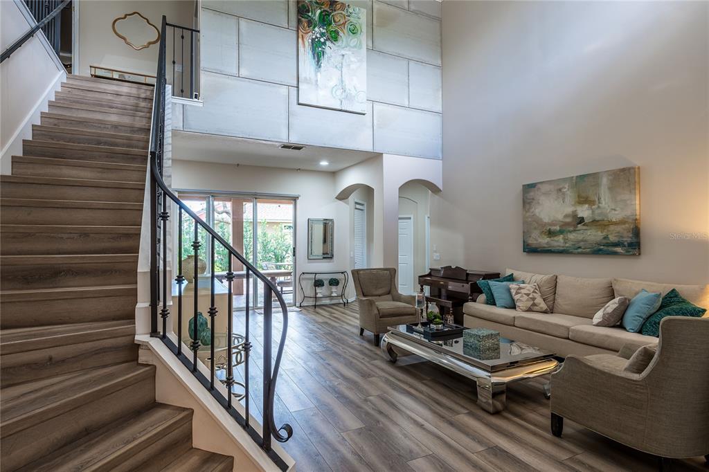 A living room with wood-look flooring, a staircase with iron railings, and high ceilings — 4642 RIVER GEM AVENUE, WINDERMERE, FL