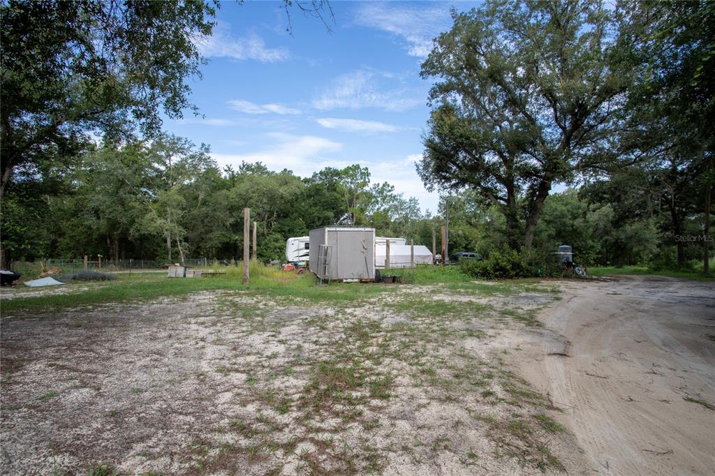 A dirt driveway leads to a small storage shed and a parked RV on wooded land — 1776 ANDERSON LANE, LADY LAKE, FL