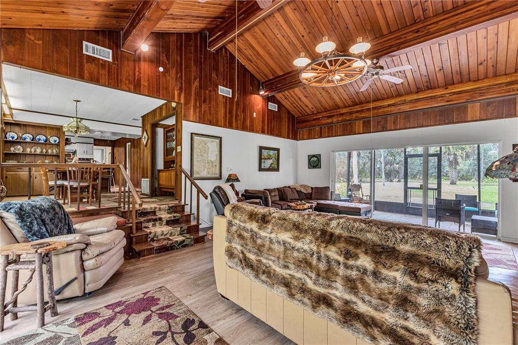 The exterior of a single-story house with a metal roof, screened porch, and concrete patio — 22308 BLUE CREEK LODGE ROAD, ASTOR, FL