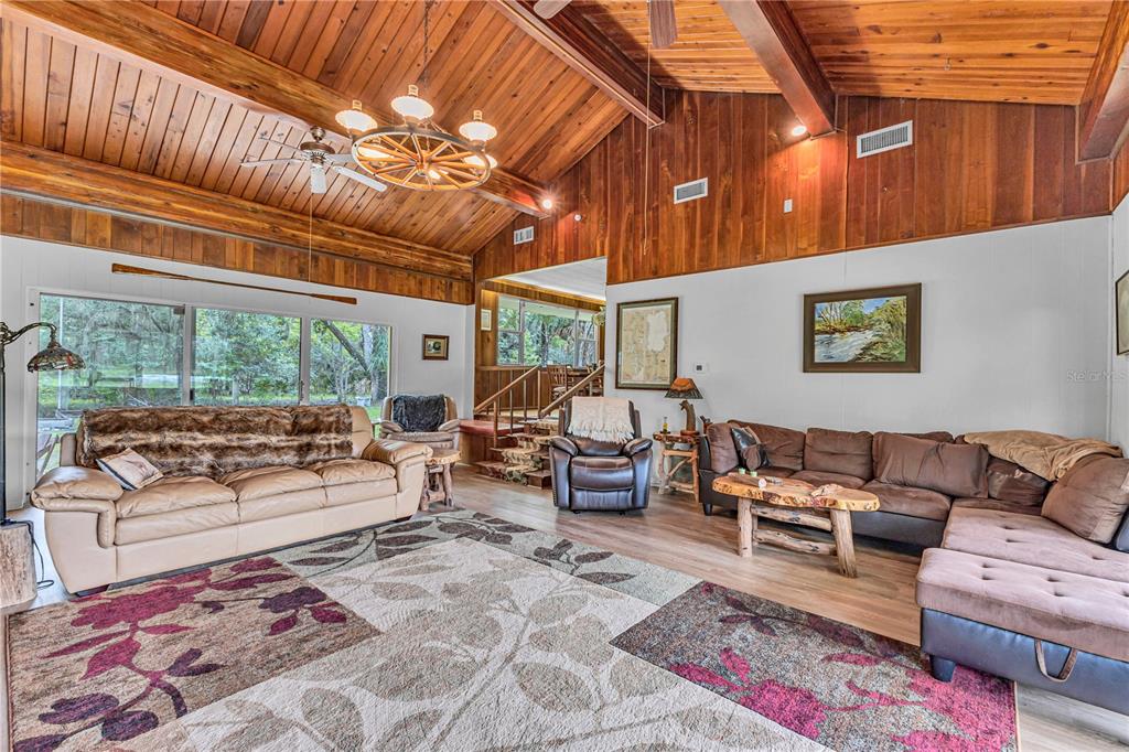 An aerial view shows several houses situated along a winding river surrounded by dense forest — 22308 BLUE CREEK LODGE ROAD, ASTOR, FL