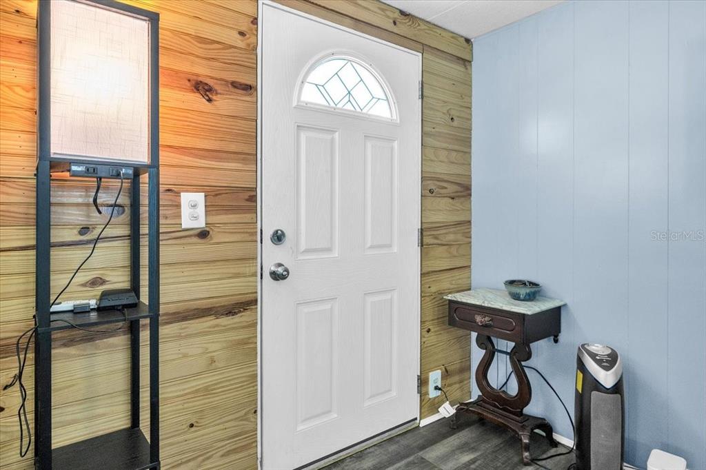 A room features a white front door flanked by wood-paneled and light blue walls — 8846 SW COULTER ROAD, ARCADIA, FL
