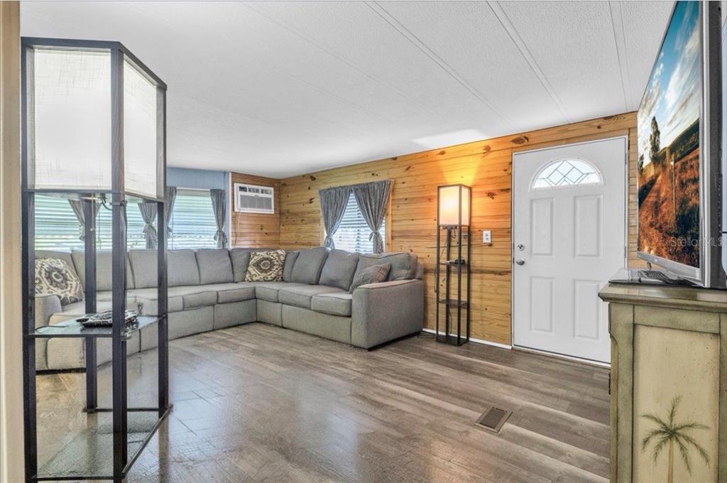 A living room features wood-paneled walls, a gray sectional sofa, and wood-look flooring — 8846 SW COULTER ROAD, ARCADIA, FL