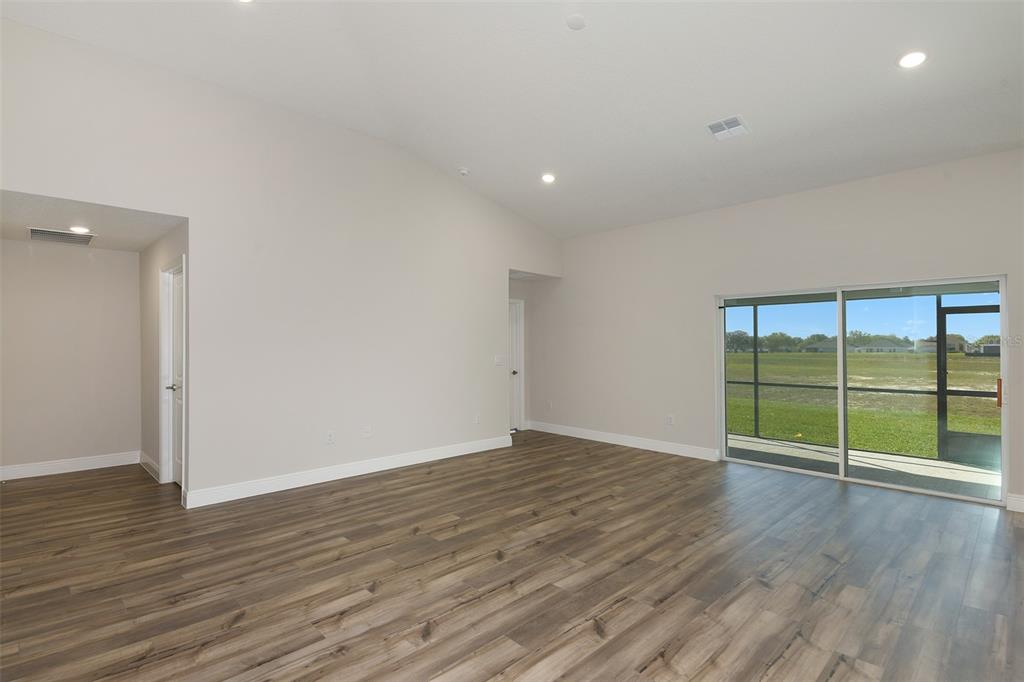 An empty room with wood-look flooring, recessed lighting, and a sliding glass door to outside — 6153 SW 97TH STREET, OCALA, FL
